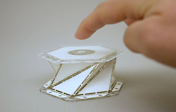 a hand pointing at a paper model of a metamaterial