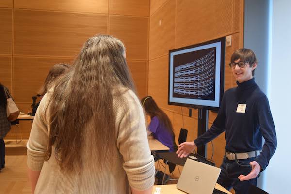 John Michael Racy talking to two people during a research showcase event