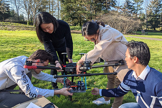 four students working on a drone outdoors