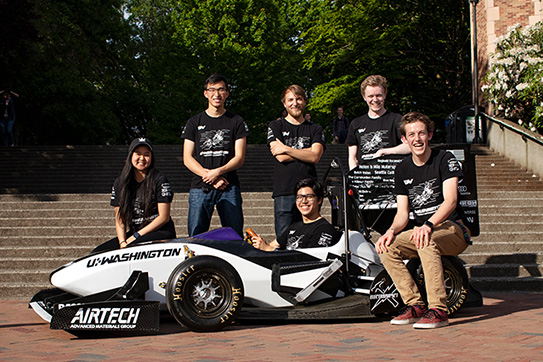 a group of students next to a race car