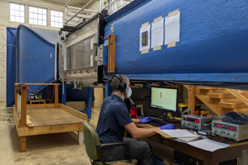 Man in a wind tunnel lab, sitting in front of a computer observing data