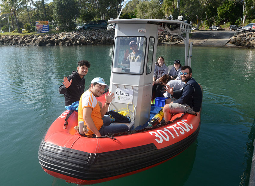 Cuadras waving from a boat with a group of students and researchers
