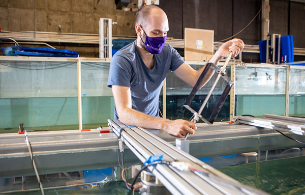 a man inspects a marine energy turbine at UW's Alice C. Tyler Flume