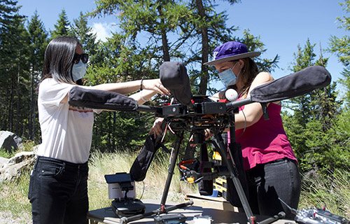 two women outside building a drone