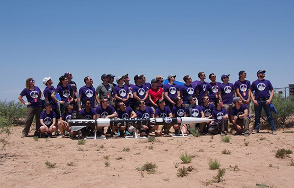 members of the SARP team posing outside with a rocket