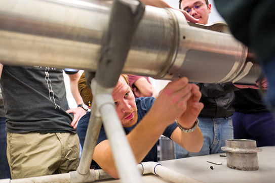 a group of students working on a metal device