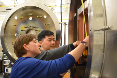 Two people working on a plasma science lab