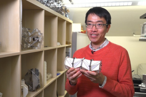 A researcher holding a chain composed of origami cells