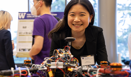 a person smiling at camera behind a robot