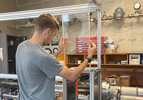 Male student adjusting a glass testing chamber