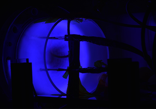 Low light photo of a circular vacuum chamber test bed in the Space Lab