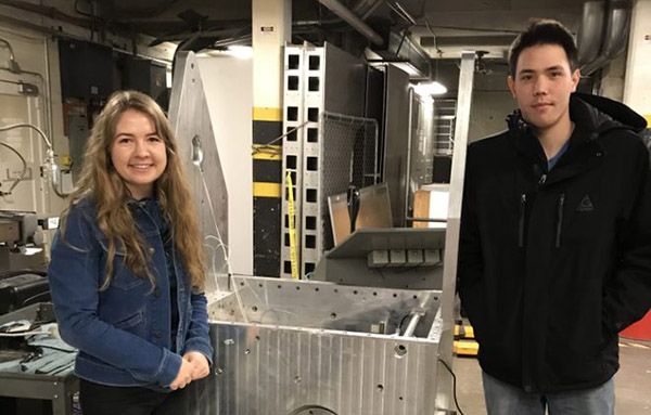 two students standing inside the wind tunnel