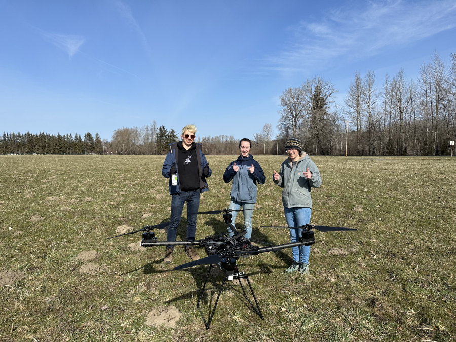 Three women standing behind a drone