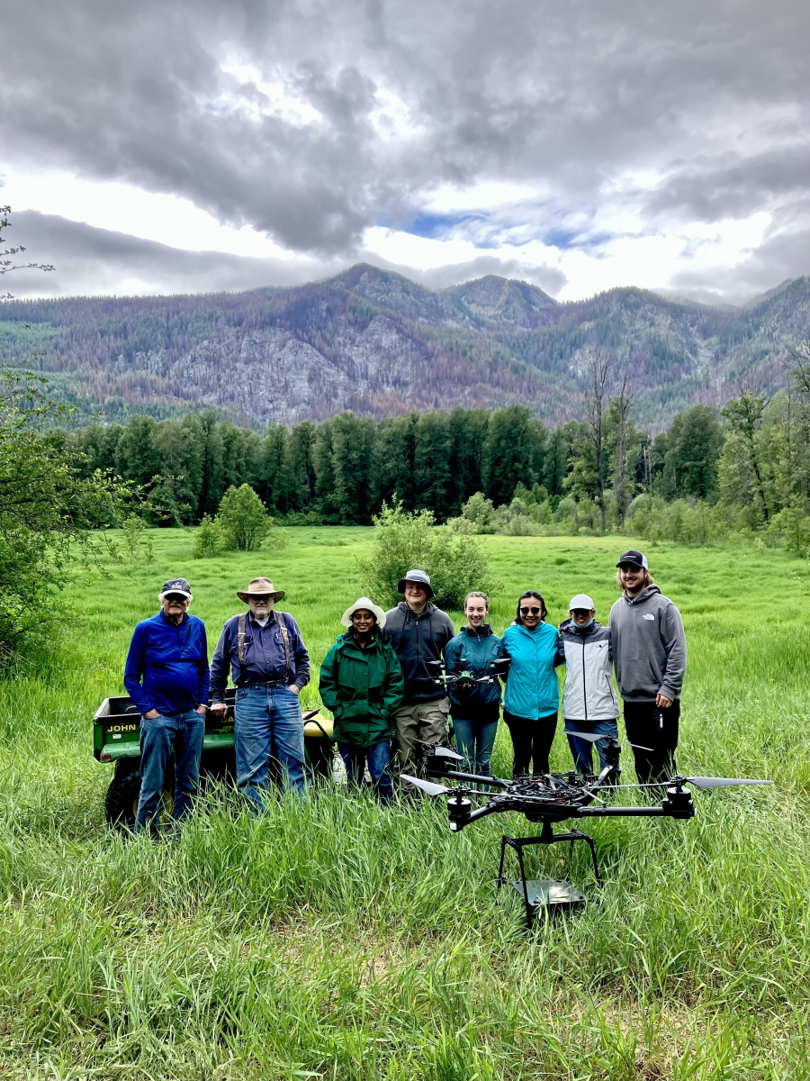 Group of people posing behind a big drone