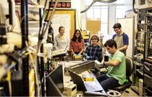 people in lab stand around rectangular box