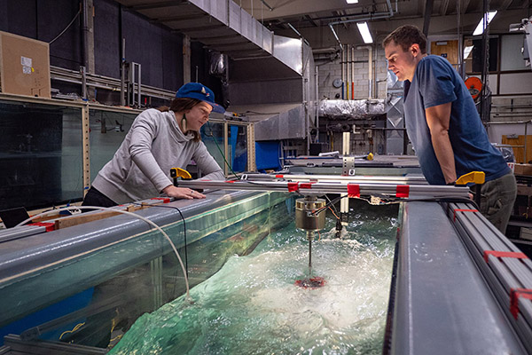 a young woman and young man observe a cross-flow turbine in the Alice C. Tyler flume in the UW Harris Hydraulics Lab