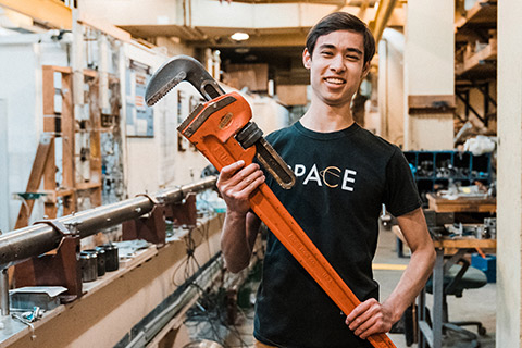 Carter Vu holding a very large wrench at a lab