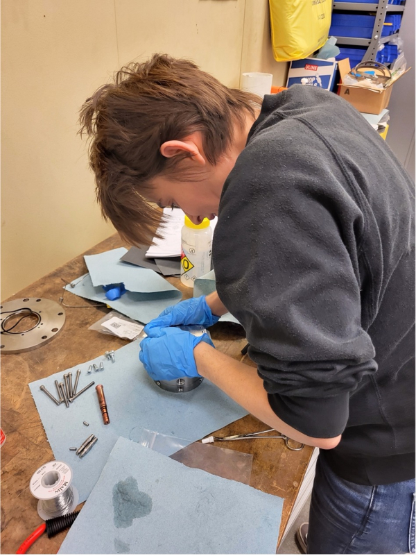 Person in a lab wearing gloves assembling a prototype