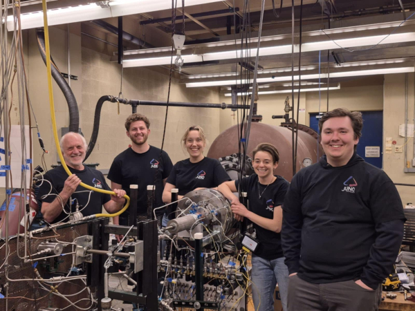 A group of five people in a laboratory setting with engineering equipment