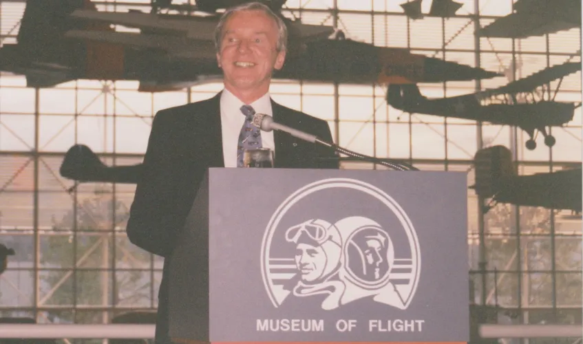 Christiansen at podium with planes hanging behind him.