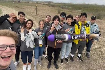Students grouped together holding a rocket