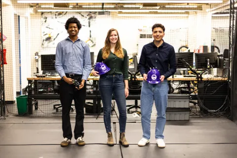 Three researchers in a lab posing to the camera with specialized equipment