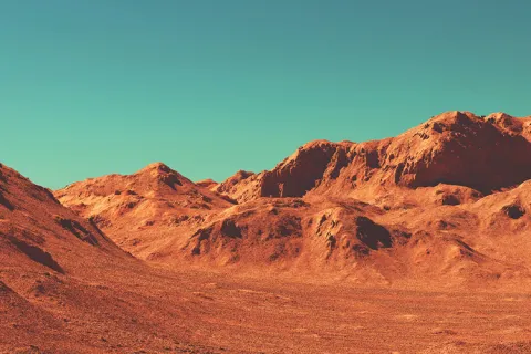 Reddish-brown mountainous landscape under a turquoise sky.